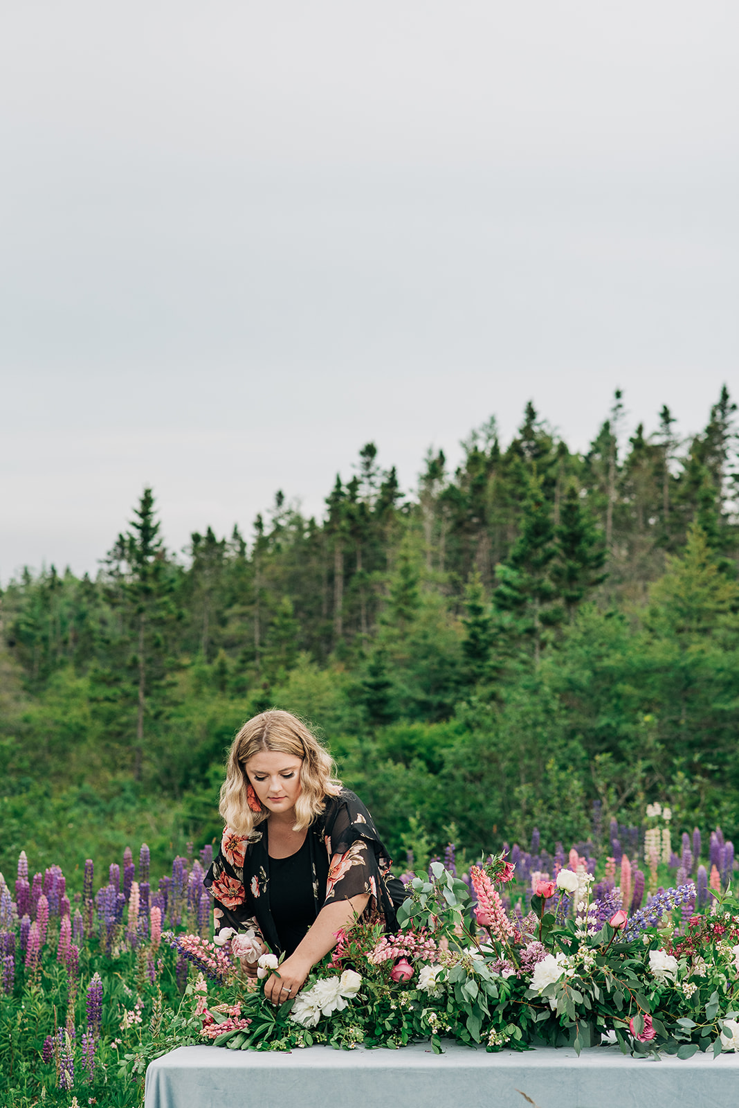 Brittany Bested of Wild Bloem Studios setting a tablescape inspired by Monet's Water Lilies in a field of lupins